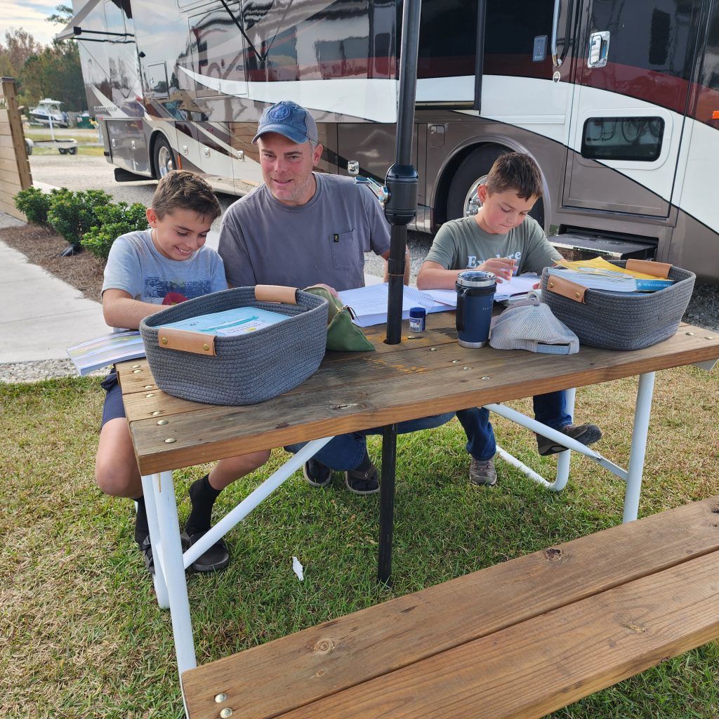 Children studying at a picnic table in the park