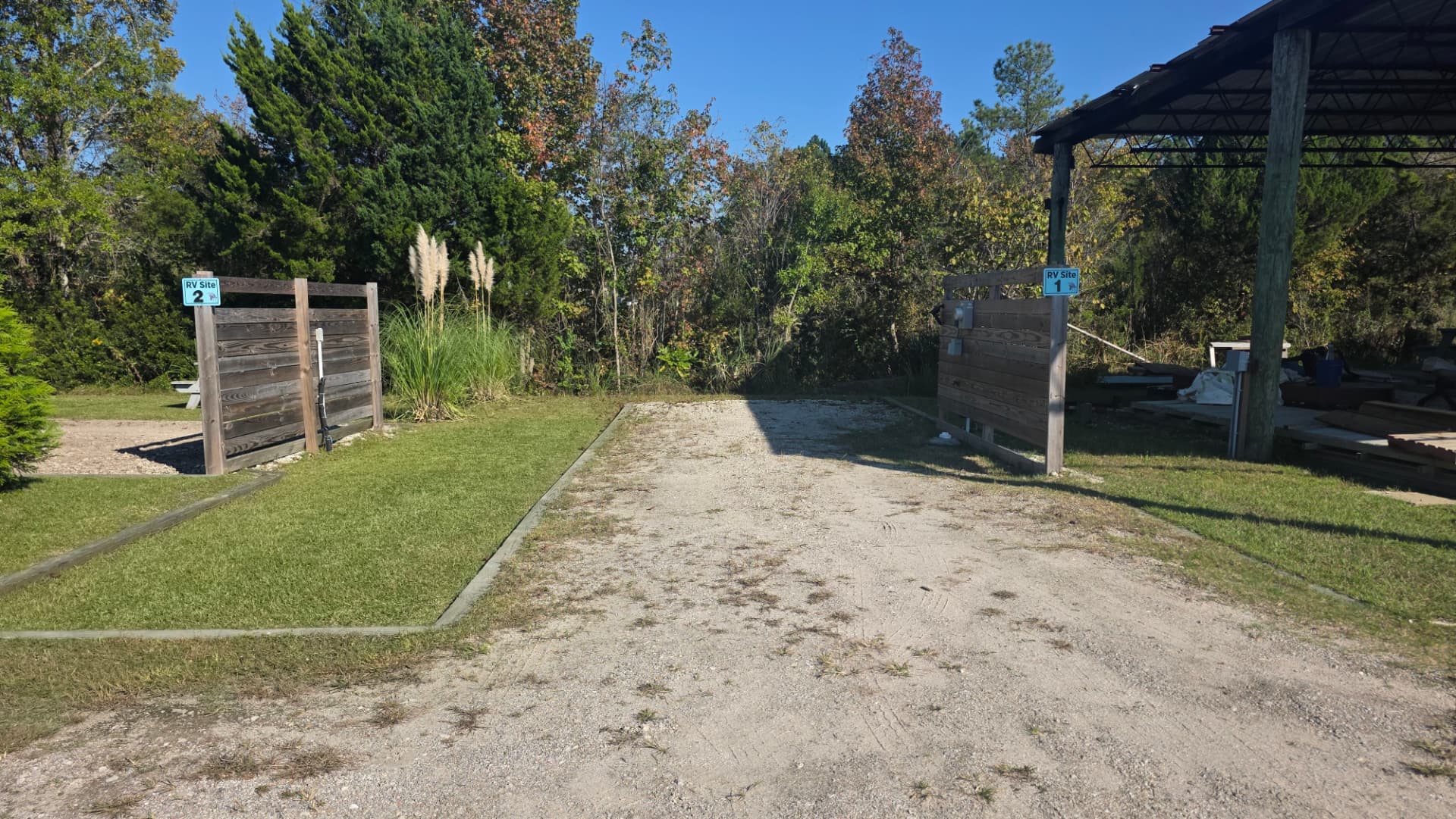 Gravel RV pad at Core Creek site CCR1-123 between timber privacy screens, with a covered pavilion alongside