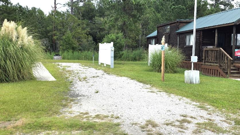 Back-in RV site RV17-162 with a gravel pad beside a cabin