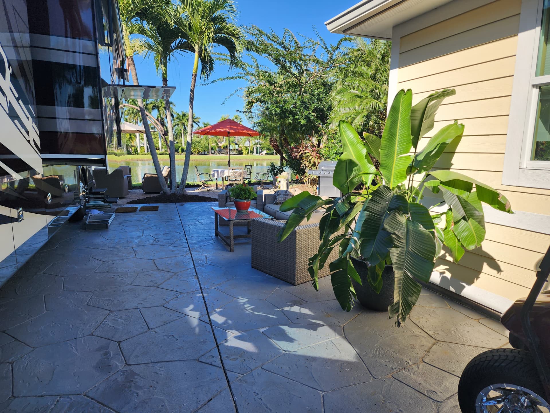 RiverBend coach house and RV lot with paver patio, outdoor seating and palm trees beside the lake