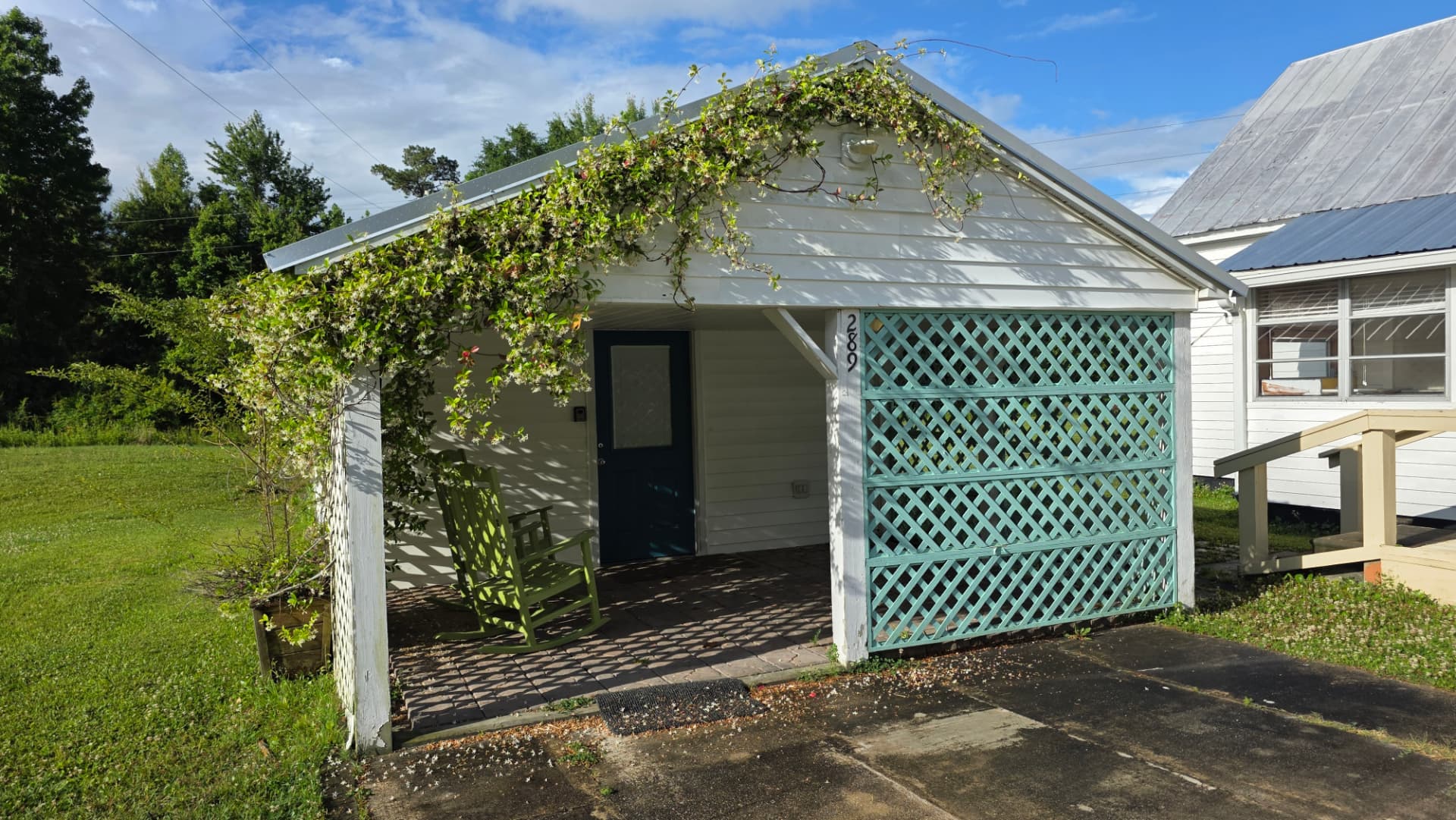 Studio apartment entrance with jasmine-covered porch, green rocking chair and teal lattice